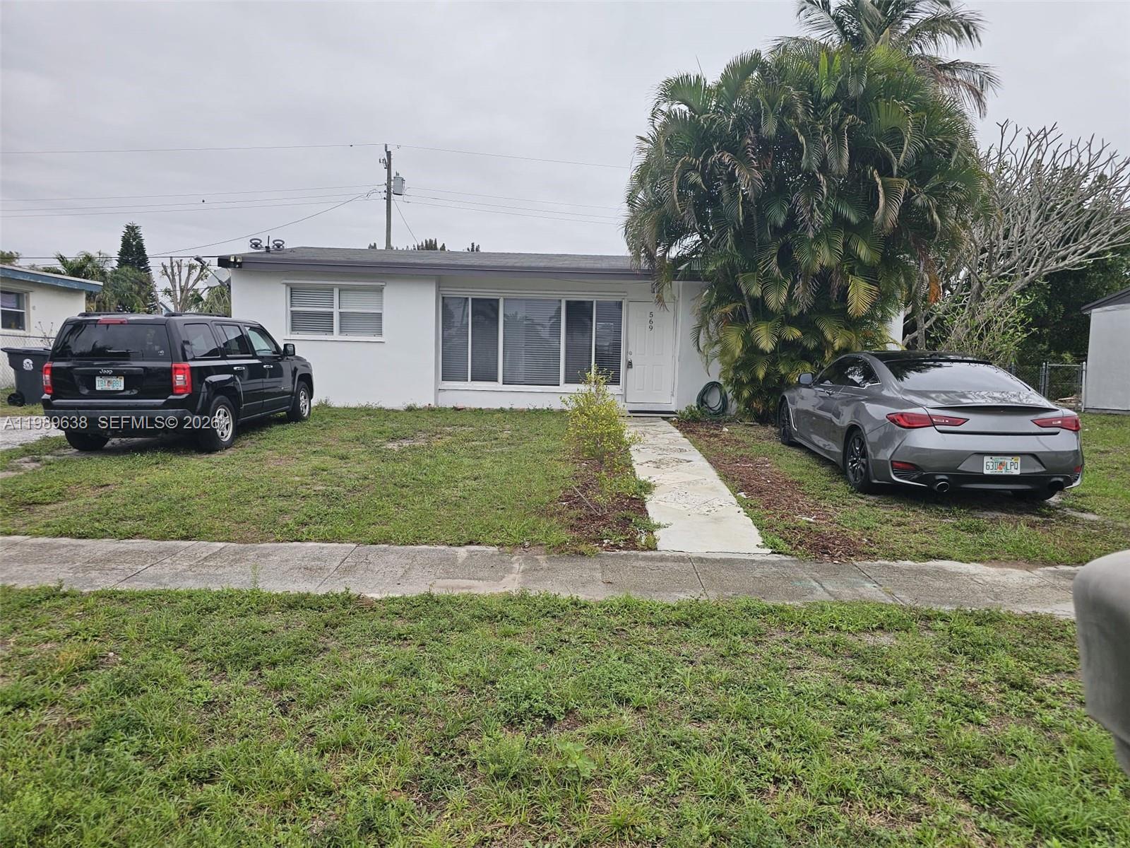 569 Tallulah Road Lake Worth, FL 33462 - Photo 38 of 40 a front view of a house with a garden and trees