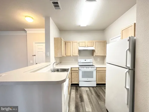a kitchen with a sink a refrigerator and white stove top oven