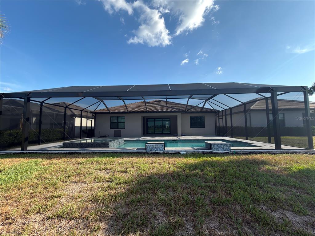 18334 Ridgeline Drive Estero, FL 33928 - Photo 22 of 30 a view of a large pool with a lawn chairs under an umbrella with a big yard