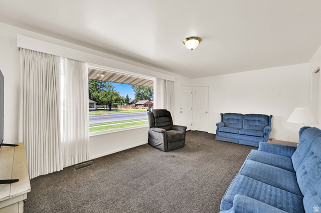 2467 South 2000 West Syracuse, UT 84075 - Photo 13 of 28 Spacious living area featuring a large picture window, neutral carpeting, white walls, and a ceiling-mounted light fixture