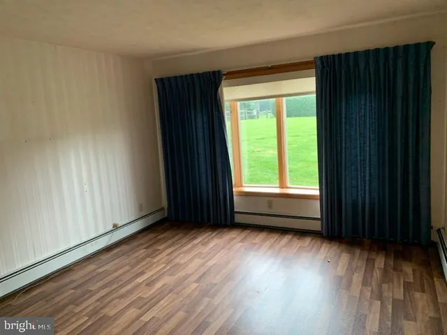 a view of an empty room with wooden floor and cabinets