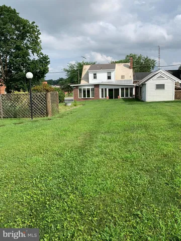 a view of a white house with a big yard and large trees