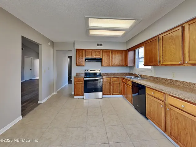 a large kitchen with stainless steel appliances granite countertop a stove sink and cabinets