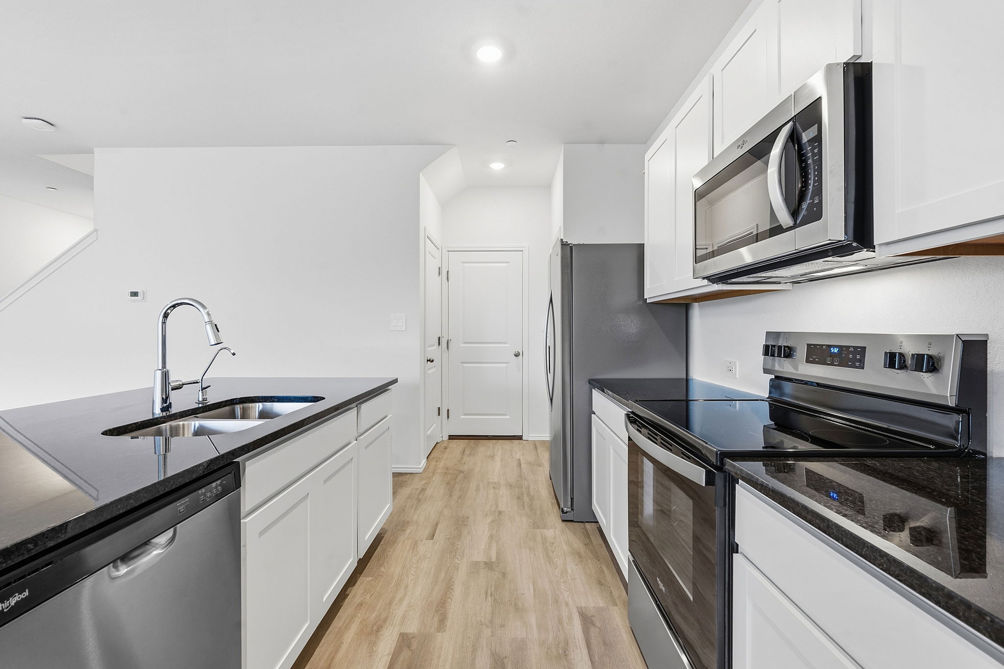 164 Cinnabar Lane, Unit 2 Kyle, TX 78640 - Photo 7 of 21 Kitchen featuring wood-finish flooring, white cabinetry, dark countertops, and stainless steel appliances including a refrigerator, range, microwave, and dishwasher