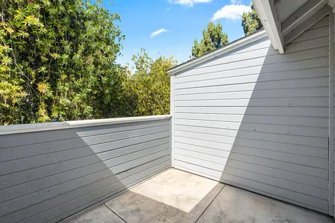 a view of a balcony with wooden fence and large trees
