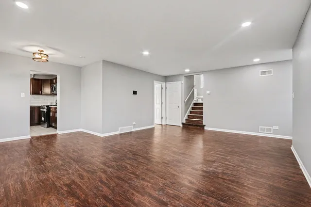 a view of an empty room with wooden floor and stairs
