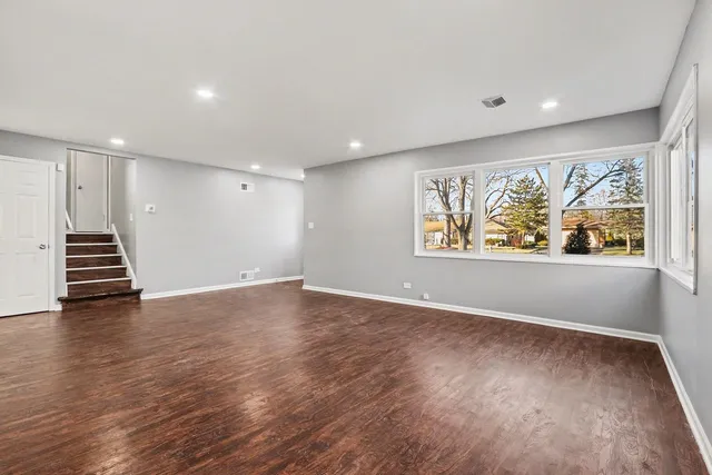 a view of an empty room with wooden floor and painting on the wall