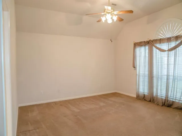 an empty room with a chandelier fan and windows