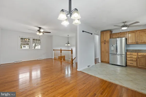 a view of a kitchen with a sink a refrigerator a chandelier and wooden floor