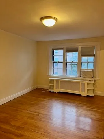 a view of an empty room with a window and wooden floor