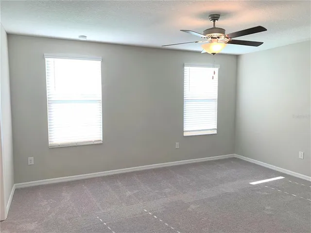 an empty room with a window and a fan