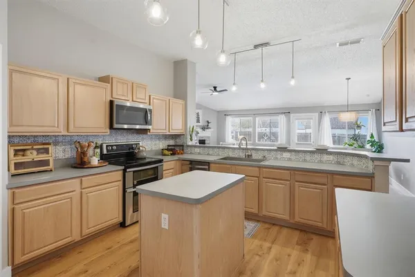 a kitchen with stainless steel appliances granite countertop a sink a stove a refrigerator cabinets and a center island