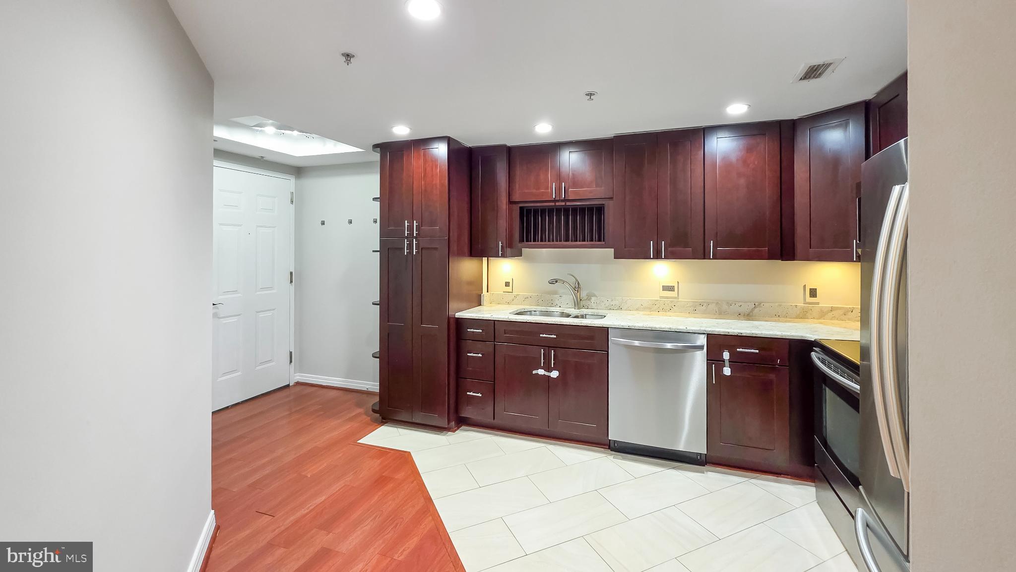 2301 N Street Northwest, Unit 404 Washington, DC 20037 - Photo 2 of 21 a kitchen with kitchen island granite countertop wooden cabinets and stainless steel appliances