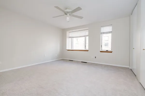 an empty room with windows and fan