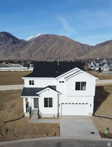 View of front of home with a garage, a mountain view, board and batten siding, a standing seam roof, and concrete driveway
