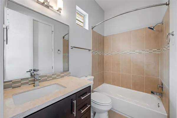 a bathroom with a granite countertop sink a toilet and shower