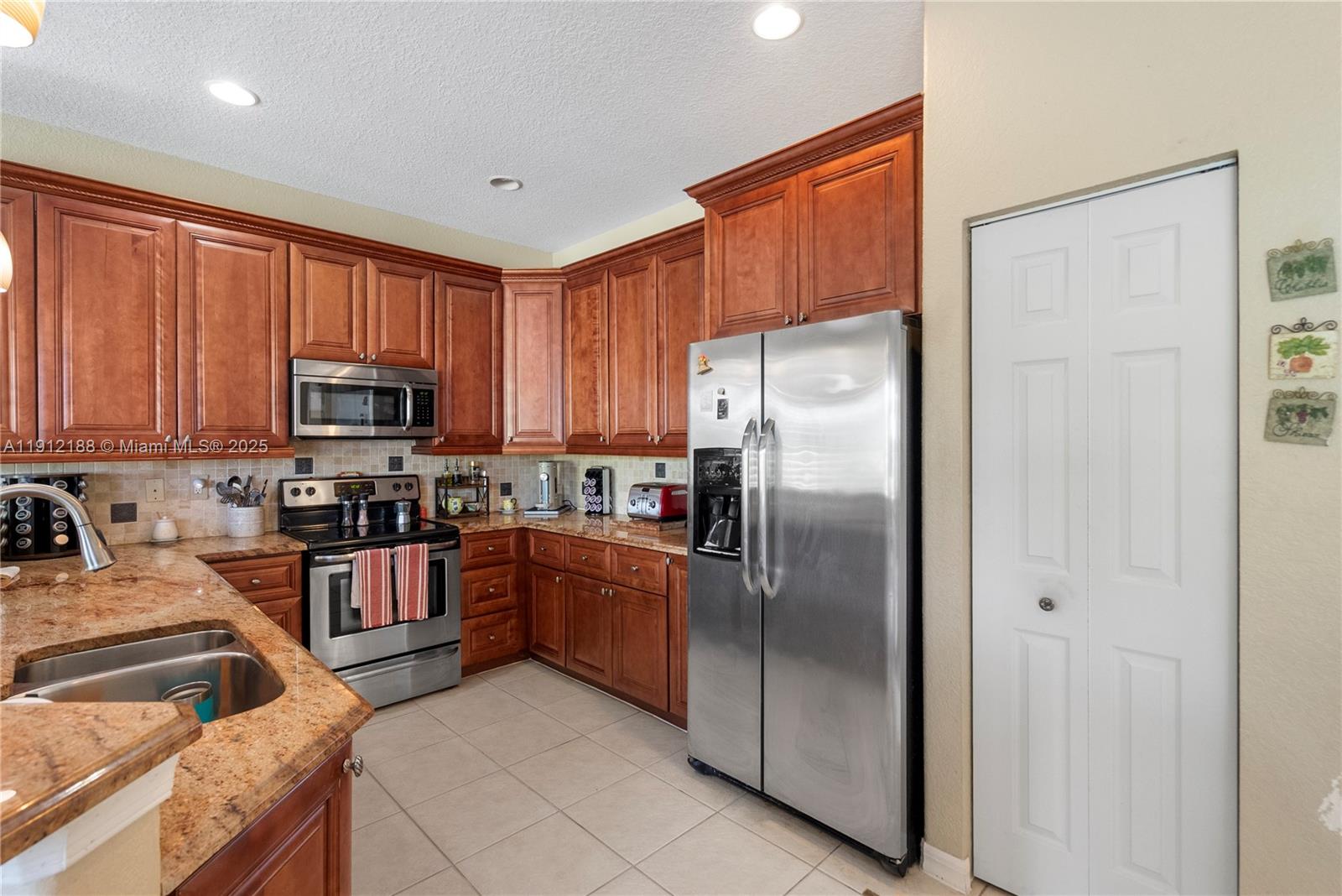 2795 Southeast Stonebriar Way Stuart, FL 34997 - Photo 25 of 54 a kitchen with stainless steel appliances granite countertop a refrigerator oven a sink dishwasher and a refrigerator with wooden cabinets