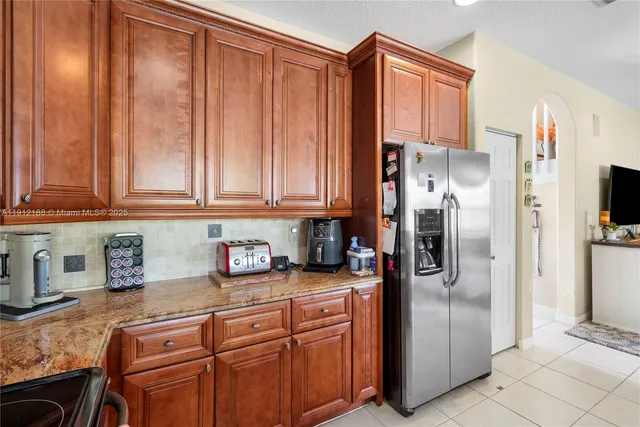 a kitchen with stainless steel appliances kitchen island granite countertop a sink a stove and a refrigerator
