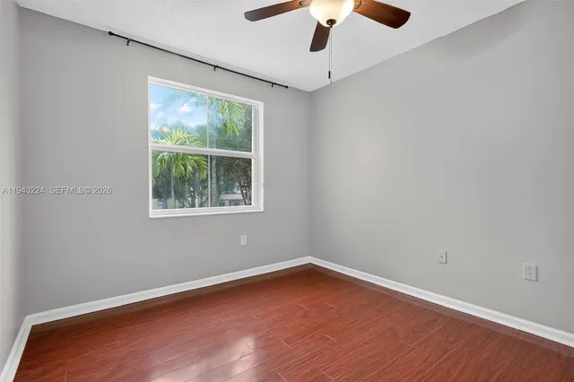 an empty room with wooden floor and ceiling fan