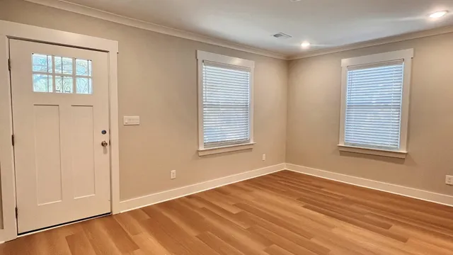 a view of an empty room with wooden floor and a window