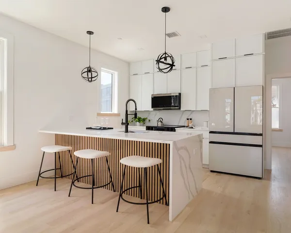 a kitchen with stainless steel appliances a white table chairs and a wooden floor
