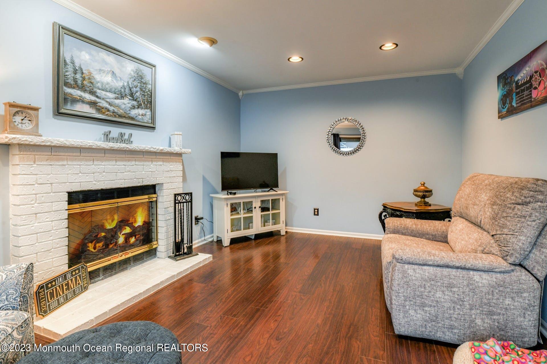 98 Starlight Road Howell, NJ 07731 - Photo 9 of 31 a living room with furniture a flat screen tv and a fireplace