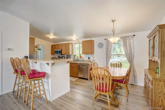 a kitchen with stainless steel appliances kitchen island granite countertop a dining table chairs and white cabinets