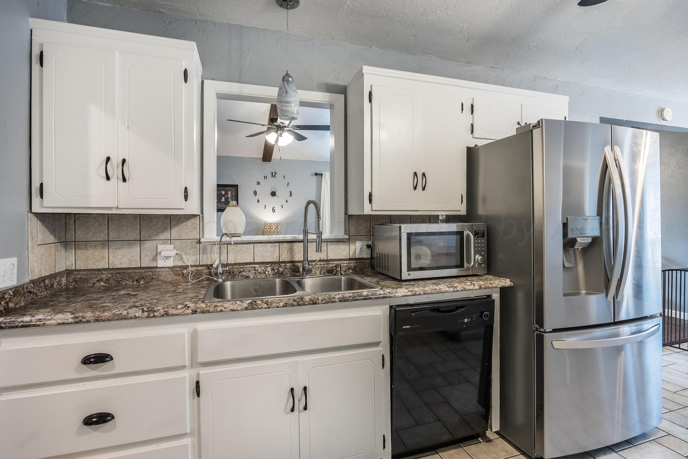 8116 Coronado Trail Amarillo, TX 79110 - Photo 8 of 18 a kitchen with stainless steel appliances granite countertop a refrigerator a stove and white cabinets