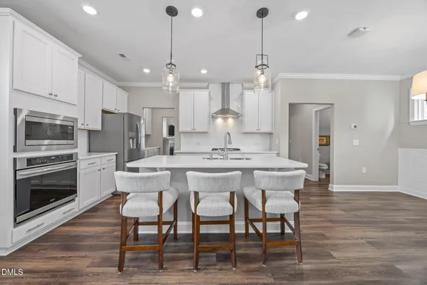 a kitchen with stainless steel appliances a dining table chairs stove microwave and cabinets