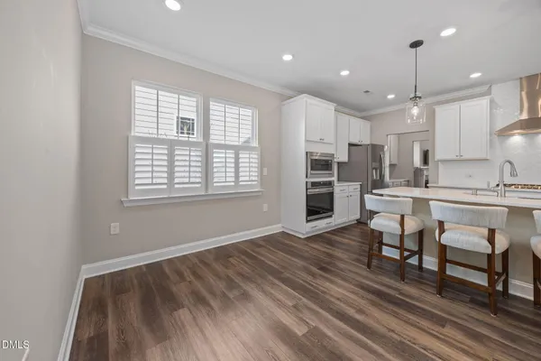 a kitchen with stainless steel appliances kitchen island granite countertop a dining table chairs sink and microwave