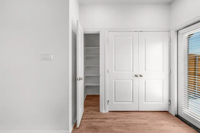 a view of a hallway with wooden floor and closet