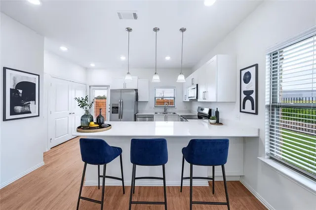 a kitchen with stainless steel appliances kitchen island a table chairs refrigerator and sink