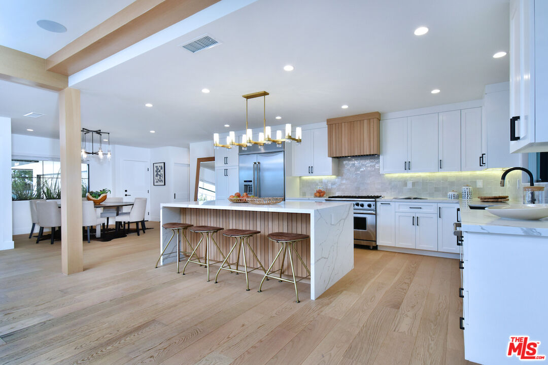 2037 Stradella Road Los Angeles, CA 90077 - Photo 8 of 33 a kitchen with a dining table chairs stainless steel appliances and cabinets