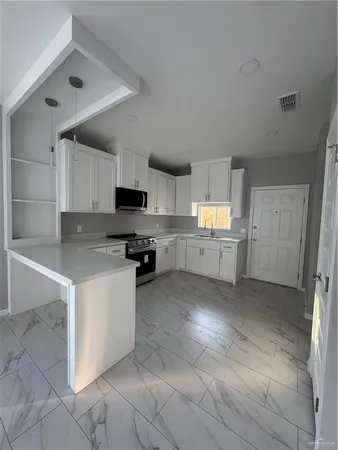 a kitchen with granite countertop a refrigerator and a stove top oven