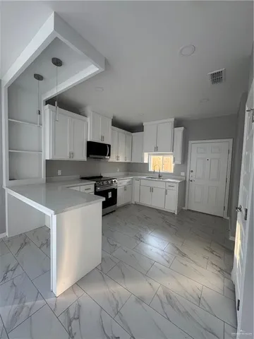 a kitchen with granite countertop a refrigerator and a stove top oven