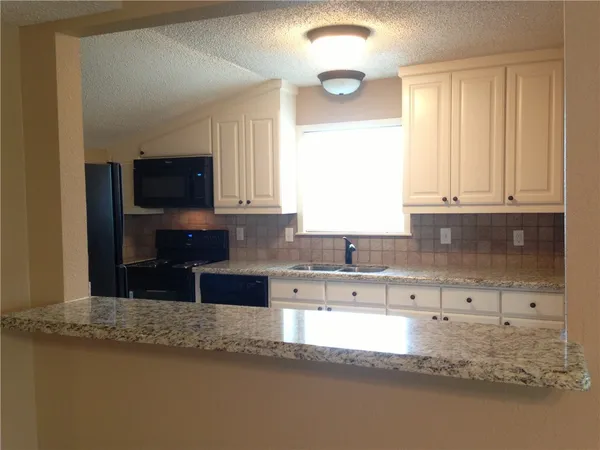a kitchen with granite countertop a stove a sink and a granite counter tops