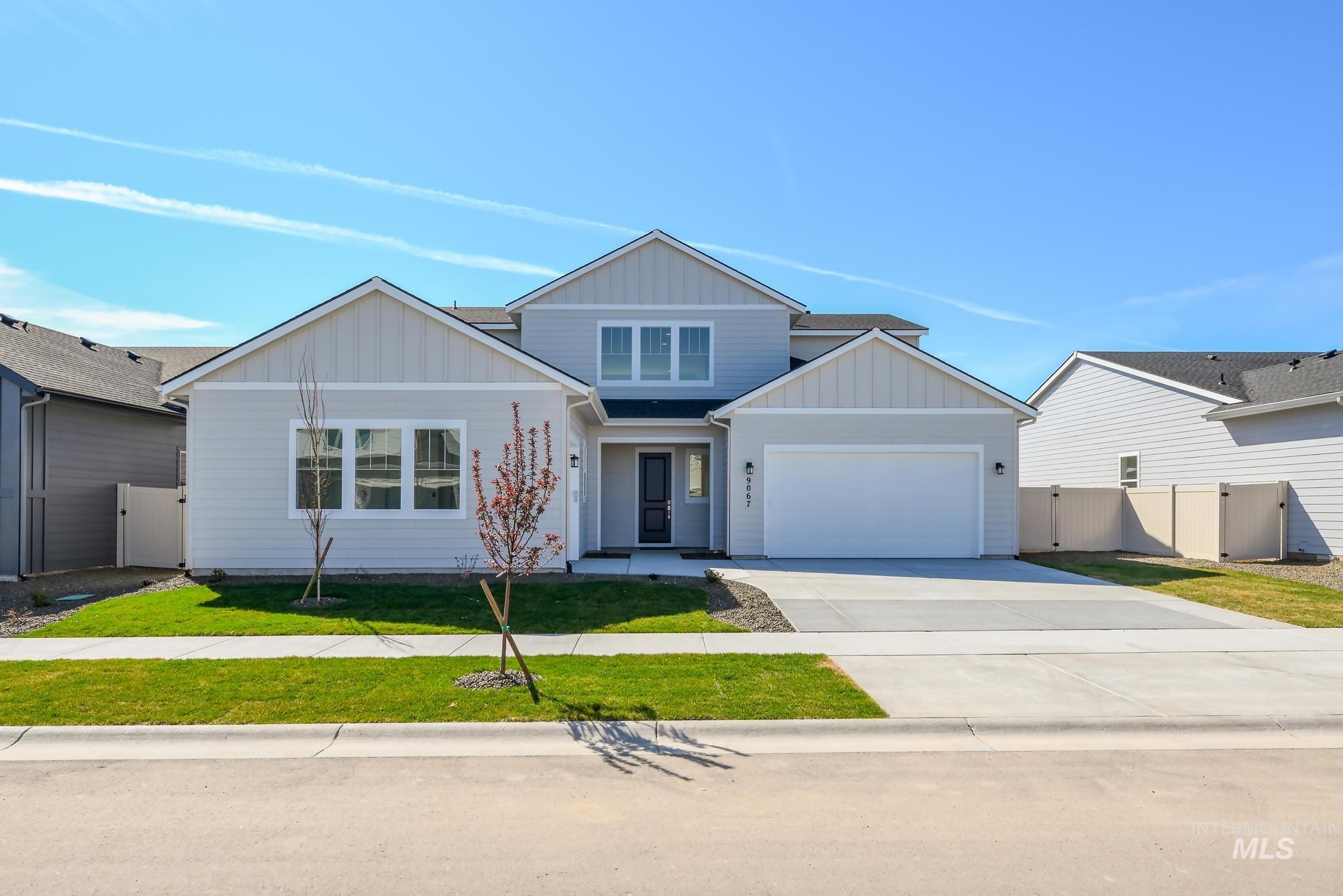 View of front facade featuring a gate, board and batten siding, concrete driveway, and a garage