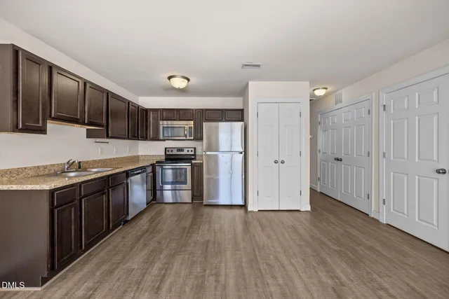 a kitchen with stainless steel appliances granite countertop a refrigerator a sink dishwasher a stove with wooden floors and cabinets