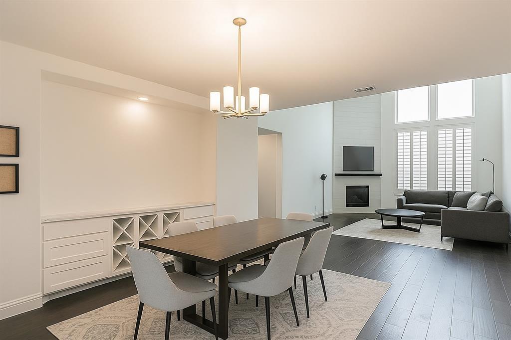 1908 Grey Bark Street Fort Worth, TX 76008 - Photo 4 of 31 Dining area featuring a fireplace, dark wood-type flooring, and a chandelier