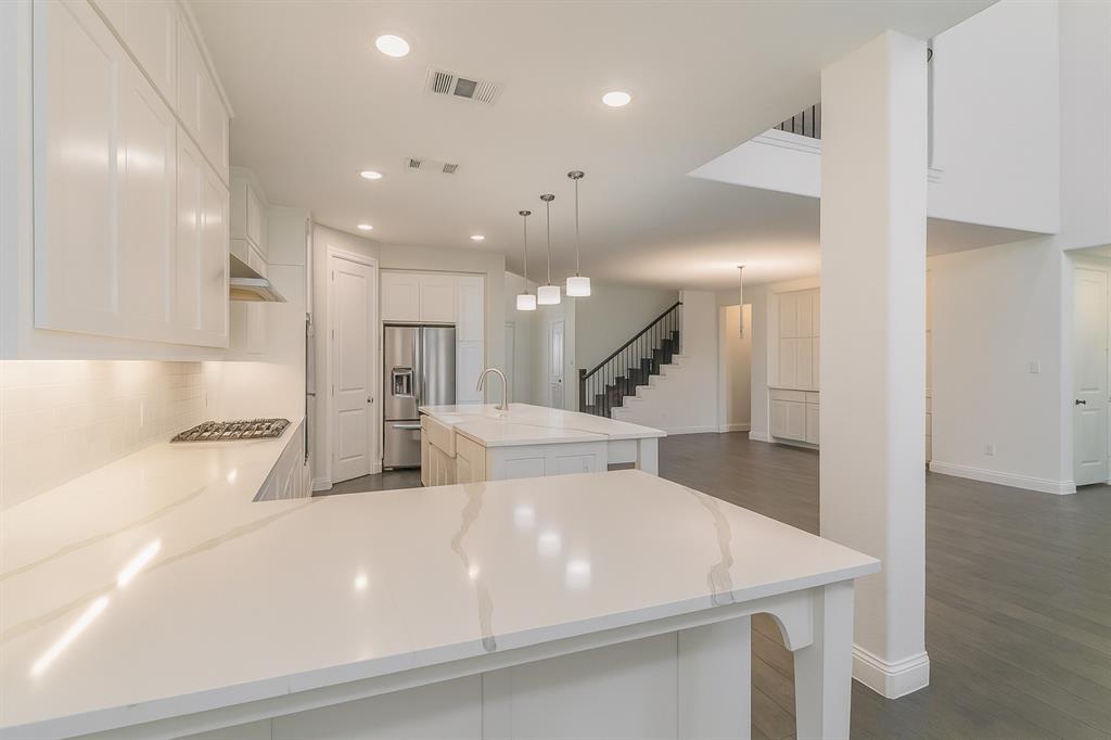 1908 Grey Bark Street Fort Worth, TX 76008 - Photo 8 of 31 Kitchen with stainless steel appliances, pendant lighting, white cabinets, recessed lighting, and light stone counters