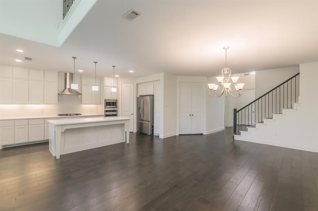 1908 Grey Bark Street Fort Worth, TX 76008 - Photo 9 of 31 Kitchen featuring decorative light fixtures, white cabinets, wall chimney range hood, and appliances with stainless steel finishes