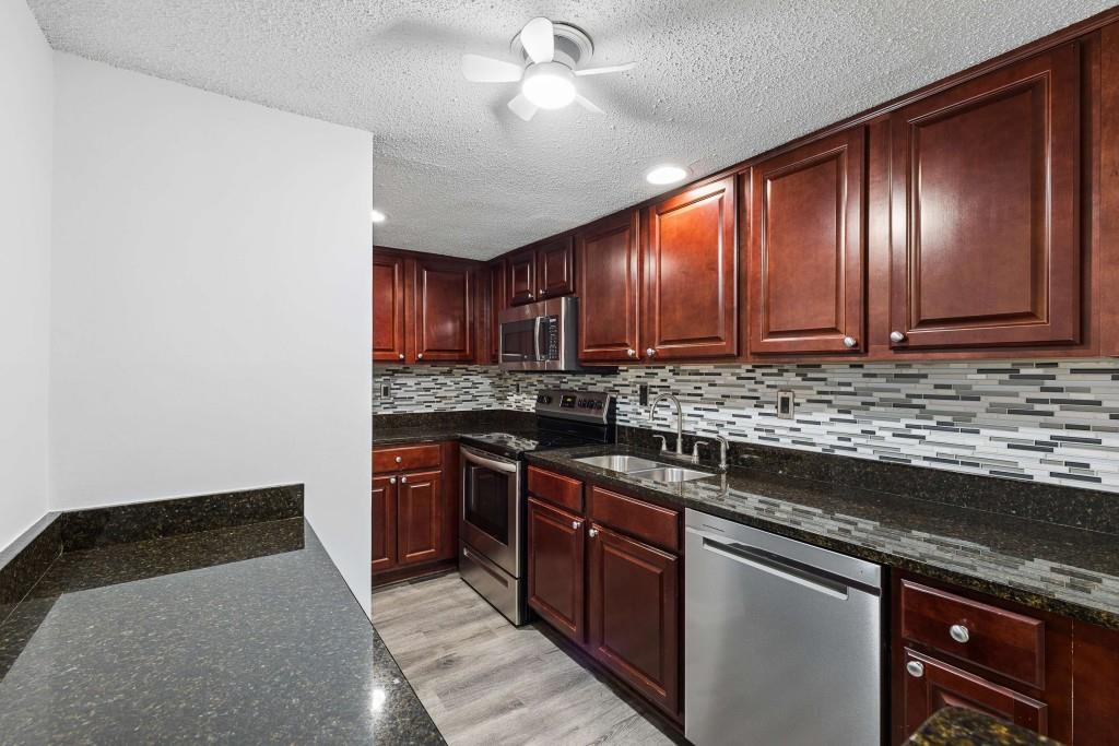 6900 Roswell Road, Unit Q6 Atlanta, GA 30328 - Photo 12 of 38 a kitchen with stainless steel appliances granite countertop wooden cabinets a stove top oven a sink and dishwasher