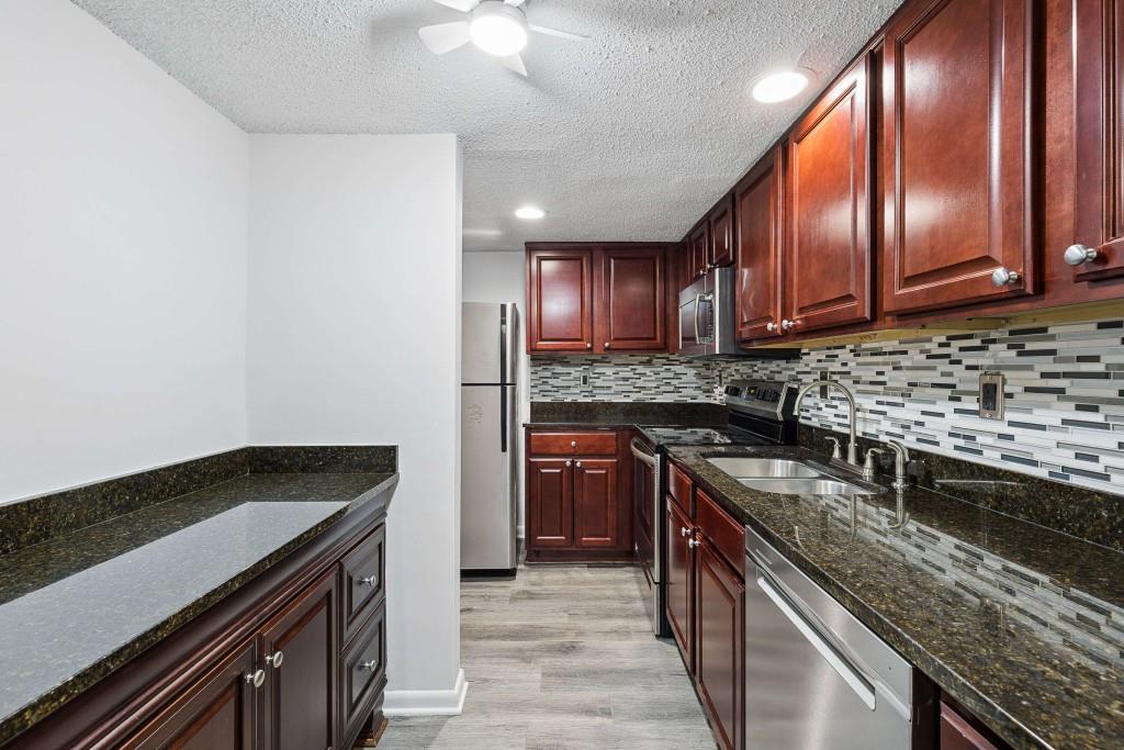 6900 Roswell Road, Unit Q6 Atlanta, GA 30328 - Photo 14 of 38 a kitchen with granite countertop stainless steel appliances and wooden cabinets