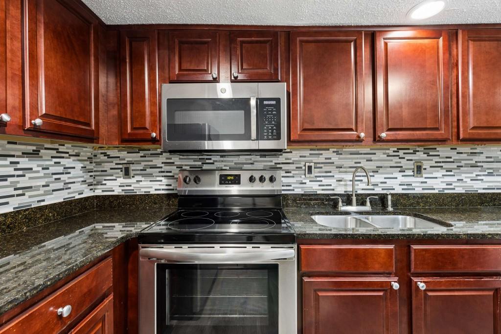 6900 Roswell Road, Unit Q6 Atlanta, GA 30328 - Photo 17 of 38 a kitchen with granite countertop stainless steel appliances and wooden cabinets