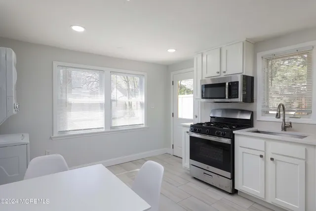 a kitchen with stainless steel appliances a stove sink microwave and window