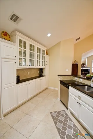 a large white kitchen with granite countertop a sink and white cabinets
