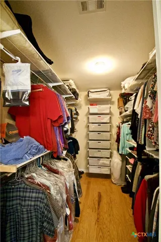 a view of walk in closet with clothes and shoes