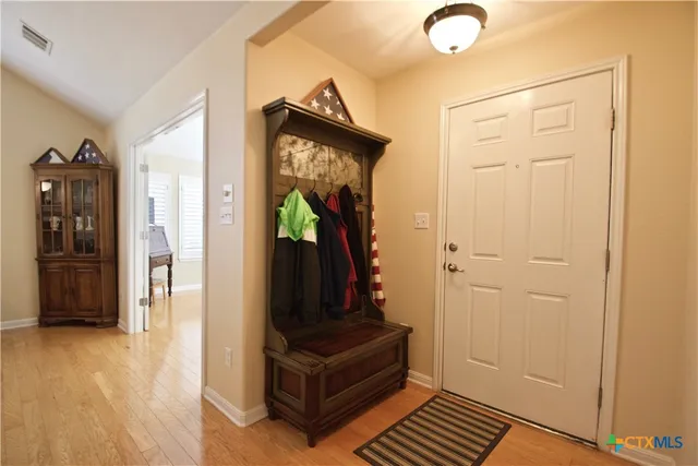a view of a entryway door with hallway and wooden floor