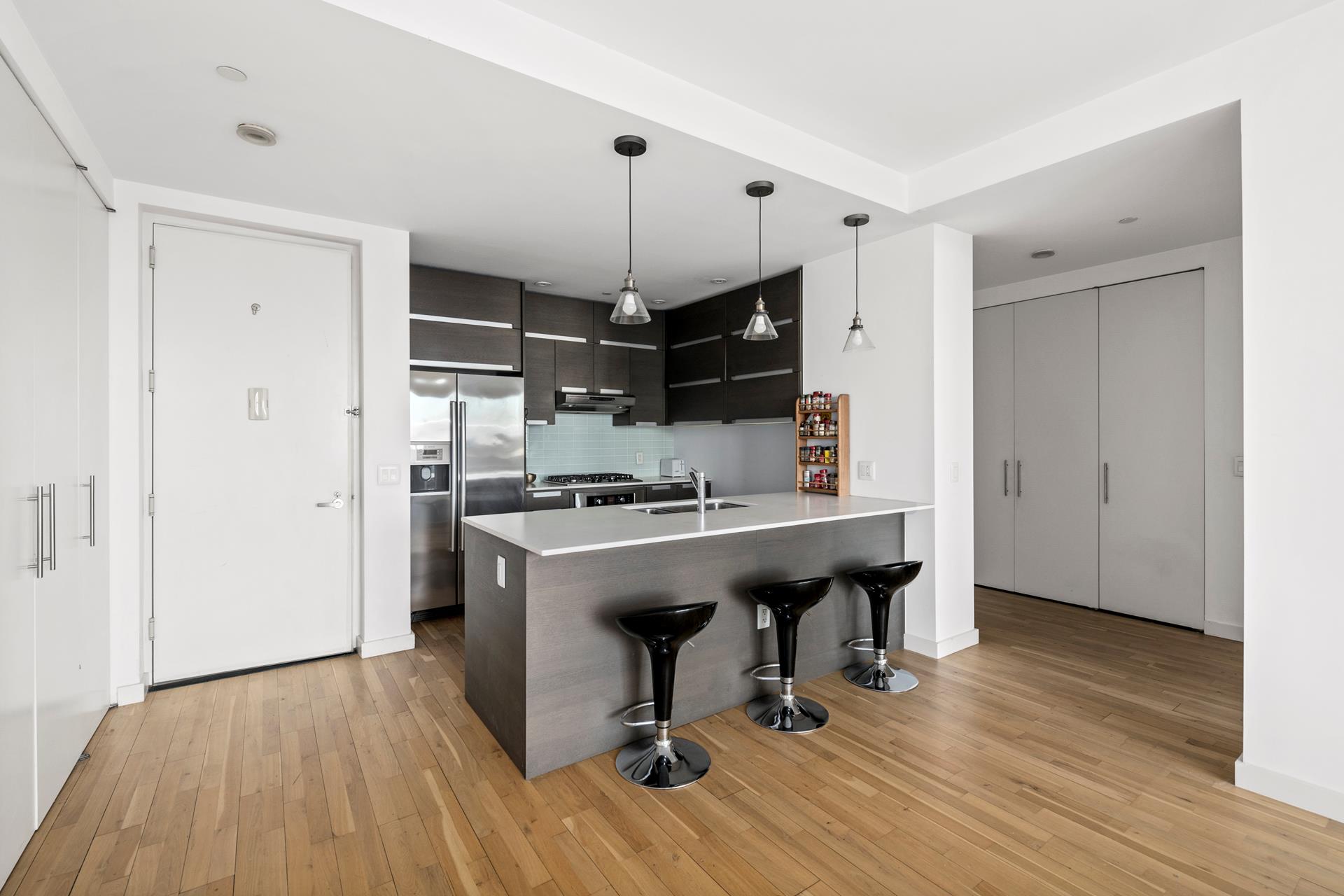 a view with kitchen island stainless steel appliances wooden floor and living room view