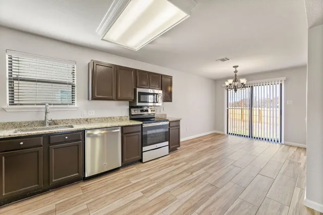 a large kitchen with stainless steel appliances granite countertop a stove a sink dishwasher and a microwave oven with wooden floor